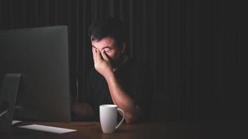 conceito de fadiga ocular. homem tocando seus olhos porque cansado depois de trabalhar muito tempo no computador foto