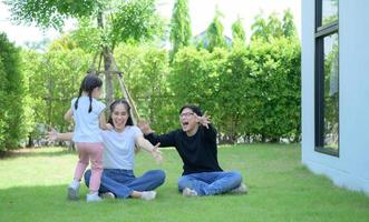 família asiática com pai, mãe e filha se divertindo no jardim da casa alegremente foto