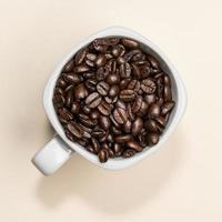 grãos de café em xícara branca sobre fundo colorido foto
