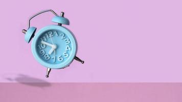 despertador vintage azul flutuando no ar com fundo de parede rosa foto