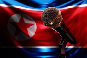 microfone no fundo da bandeira nacional da coreia do norte, ilustração 3d realista. prêmio de música, karaokê, rádio e equipamentos de som de estúdio de gravação foto