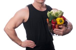 homem musculoso segurando frutas e legumes foto