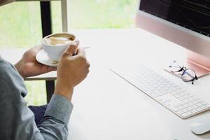 trabalhe em casa um funcionário da empresa segurando uma xícara de café usando um computador para trabalhar em casa para evitar que o coronavírus conheça pessoas de fora. foto