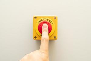 botão de parada e a mão do trabalhador prestes a pressioná-lo. botão de parada de emergência. grande botão de emergência vermelho ou botão de parada para pressão manual. foto