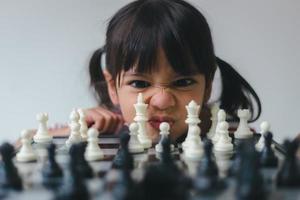 menina asiática jogando xadrez em casa. um jogo de xadrez foto