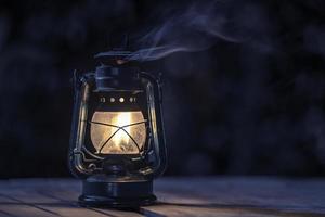 lâmpada de querosene antiga com luzes no chão de madeira no gramado à noite