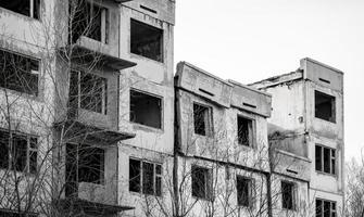 edifício residencial em ruínas com janelas vazias, telhado desmoronado, telhado desmoronado. foto preto e branco