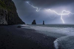 vista idílica de relâmpagos na praia preta de reynisfjara contra a noite de tempestade foto