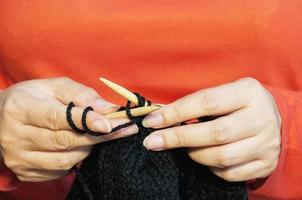 as mãos da mulher estão fazendo tricô de chapéu preto foto