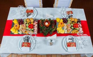 linda mesa festiva servida para jantar de festa de casamento em casa ou restaurante interior. mesa cheia de comida em um restaurante. mesa redonda completa. foto