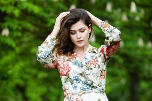 retrato de mulher com um cabelo se movendo ao vento. retrato de jovem morena russa linda no parque verde de verão. mulher branca europeia de vestido. foto