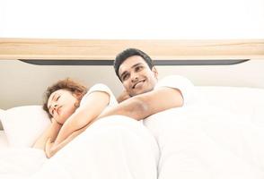 conceito de amante. jovem casal atraente deitado sob o cobertor branco na cama foto