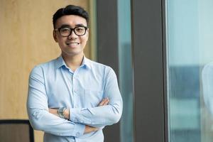 retrato masculino de empresário asiático em seu local de trabalho foto