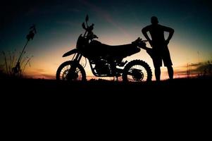 silhuetas masculinas e motos de motocross de turismo. parque para relaxar nas montanhas à noite. conceito de viagens e lazer de aventura foto