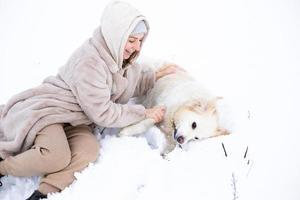 jovem mulher bonita e seu cachorro retriever dourado se divertindo no inverno. foto