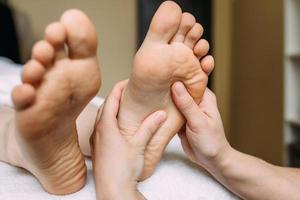 o massagista dá uma massagem nos pés femininos no spa. o conceito de procedimentos cosméticos. foto