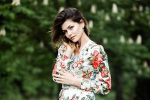 retrato de mulher com um cabelo se movendo ao vento. retrato de jovem morena russa linda no parque verde de verão. mulher branca europeia de vestido. foto