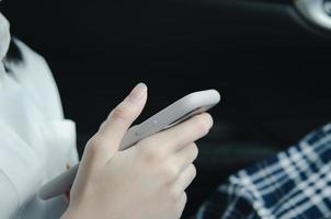 feche a mão da mulher segurando um telefone celular na cabine do carro. foto