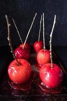 maçã de doces de halloween com vara de ouro em fundo escuro foto