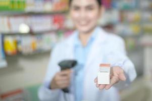 farmacêutico feminino escaneando código de barras em uma caixa de remédios em uma farmácia moderna. foto