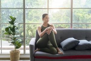 caber linda mulher asain em roupas esportivas sentada e relaxando no sofá após treino, saúde e conceito de exercício foto