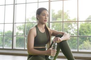 mulher jovem fitness em sportswear água potável após o exercício em casa, saudável e estilos de vida. foto