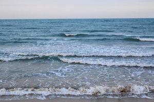 vento forte e ondas do mar atingem a costa. à noite, o fundo do mar era azul, alternando com o grão de areia por um período que a natureza criou, bonito e assustador. foto