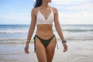 jovem mulher bonita de biquíni curtindo e relaxando na praia, verão, férias, feriados, conceito de estilos de vida. foto