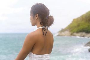 jovem mulher asiática em roupas esportivas fazendo ioga na rocha no conceito de beira-mar, saúde e meditação foto