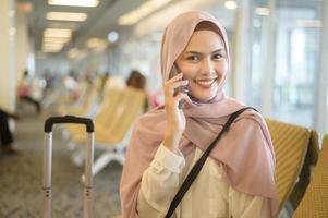 jovem viajante muçulmano feminino carregando malas no aeroporto internacional, viagens, férias e conceito de viagem. foto