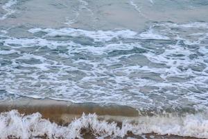 vento forte e ondas do mar atingem a costa. à noite, o fundo do mar era azul, alternando com o grão de areia por um período que a natureza criou, bonito e assustador. foto