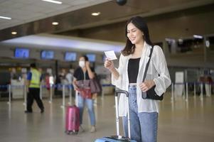 jovem viajante feminina carregando malas no aeroporto internacional, viagens, feriados e conceito de viagem. foto