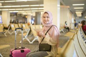 jovem viajante muçulmano feminino carregando malas no aeroporto internacional, viagens, férias e conceito de viagem. foto