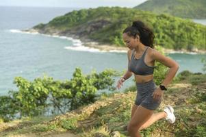 linda mulher apta no sportswear atropelando a trilha de pedra no pico da montanha à beira-mar, saúde e conceito de viagens. foto