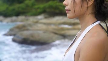 jovem mulher asiática em roupas esportivas fazendo ioga na rocha no conceito de beira-mar, saúde e meditação foto