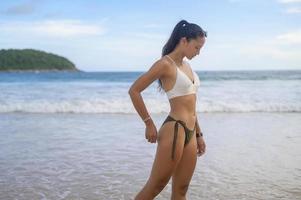 jovem mulher bonita de biquíni curtindo e relaxando na praia, verão, férias, feriados, conceito de estilos de vida. foto