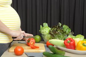 mulher grávida cozinhando com vegetais, saudável para novo conceito de família
