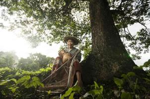 pescador de avó asiática sob grande árvore foto