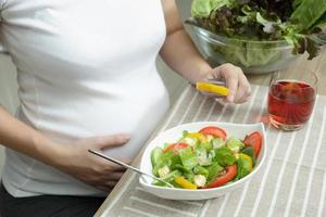 mulher grávida comendo salada de legumes, saudável para novo conceito de família foto