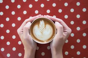 mãos de mulher segurando latte art, xícara de café. foto