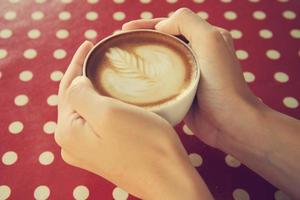 mãos de mulher segurando latte art com cor vintage foto