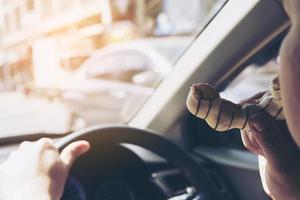 homem comendo rosquinhas enquanto dirige o carro - conceito de condução insegura multitarefa foto