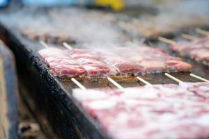 varas de carne quadrada grelhadas japonesas são dispostas na grande placa de panela com fumaça ao redor. foto