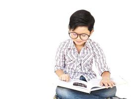 menino asiático de sete anos está lendo um livro animadamente isolado sobre o branco foto