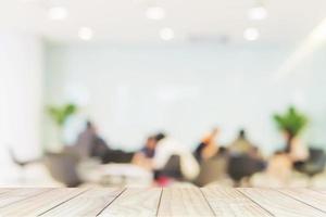 tampo da mesa de madeira branca sobre a sala de reuniões de negócios turva com pessoas discutindo foto