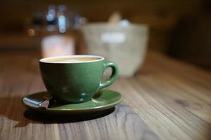 café com leite quente no copo verde na mesa de madeira foto