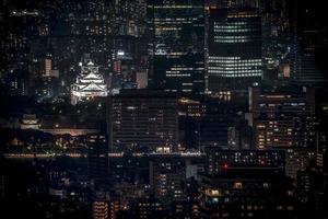 castelo de osaka iluminado à noite em birdeye ou vista superior com paisagem urbana e prédio alto ao redor, prefeitura de osaka, japão. foto