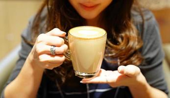 café com leite quente na mão da garota asiática, poste e pronto para beber. foto
