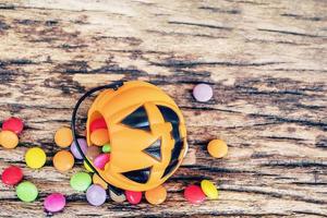 baldes de rosto de abóbora de halloween com doces coloridos dentro de textura de madeira velha foto