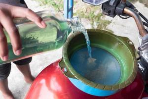 alguém está despejando combustível pertalite em uma garrafa de vidro para motocicletas, a gasolina vendida no varejo é de 1 litro foto